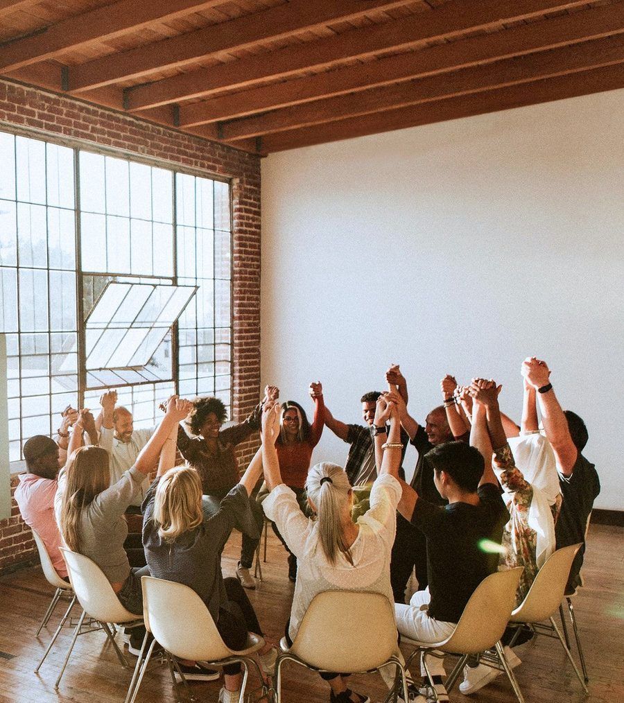 A group raising joined hands in a bright studio